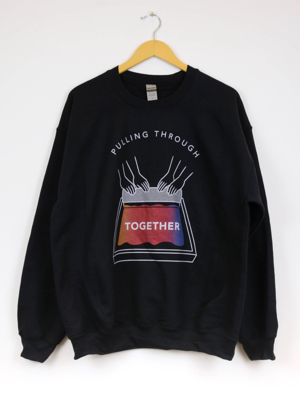 Black sweatshirt with graphic illustration of two pairs of hands pulling multicolour ink on a screen with a squeegee. The words in the graphic read "Pulling Through Together". The words ‘Pulling Through’ arch above the hands, and the word ‘Together’ is written on the silkscreen.