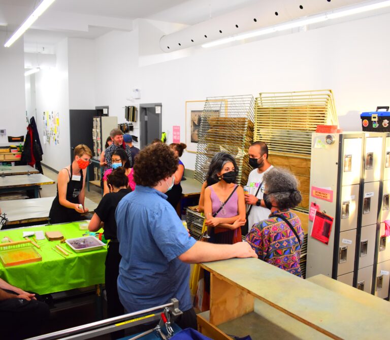 A group of people standing in SNAP printshop during an event